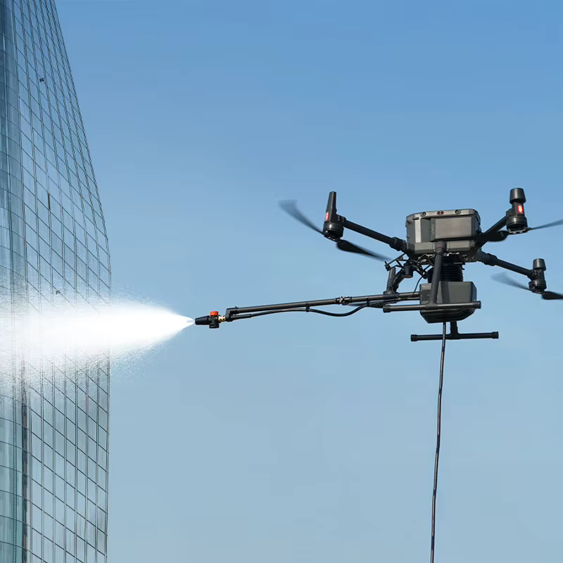 Nettoyage de façade par drone industriel haute pression Drone industriel pulvérisant de l'eau sur un gratte-ciel vitré pour le nettoyage des fenêtres.